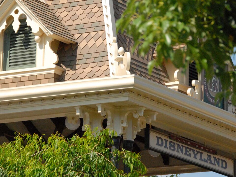 Reference photograph of a themed entertainment street facade: an ornate corner building with a decorative marquee sign, scalloped roof shingles and painted timber brackets